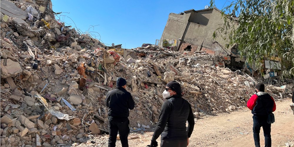 3 men in front of a pile of rubble